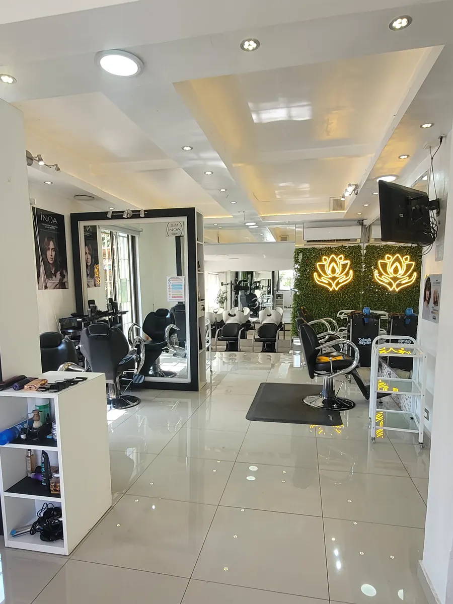 Salón amplio y luminoso, con sillones negros, espejos y la flor de loto dorada sobre un muro verde