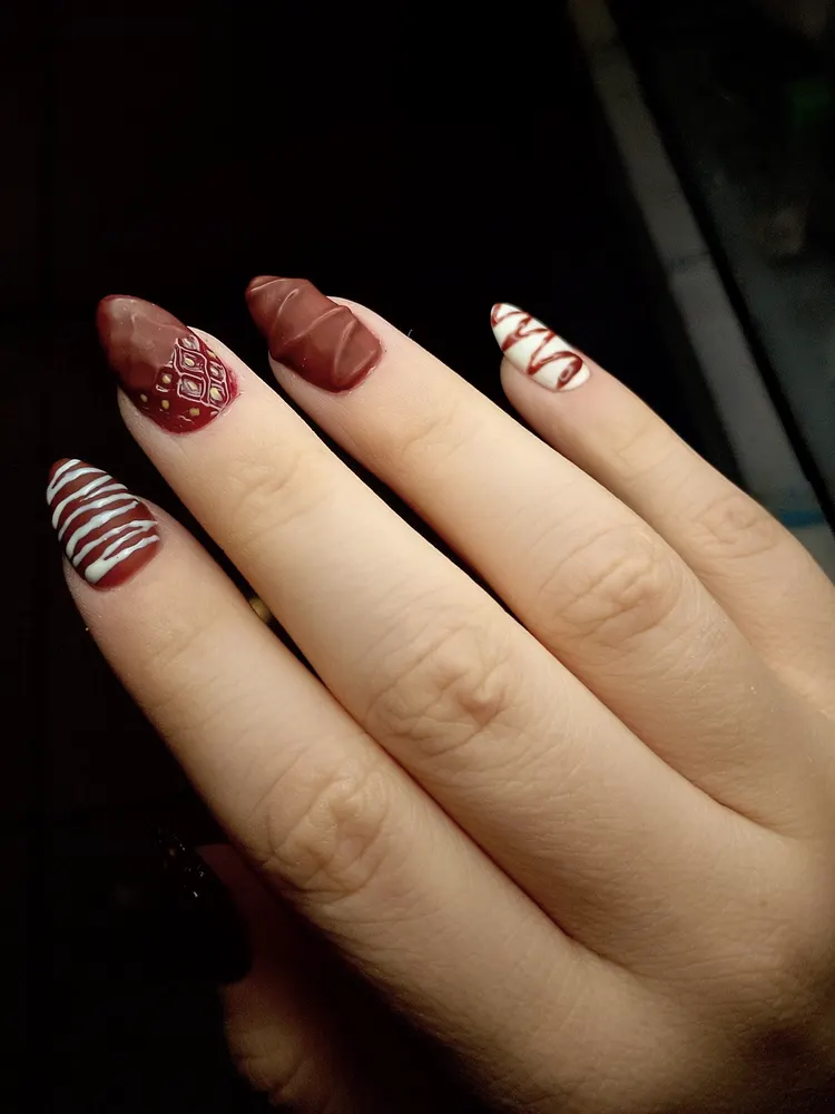 Uñas almendradas en burdeo con diseños en blanco