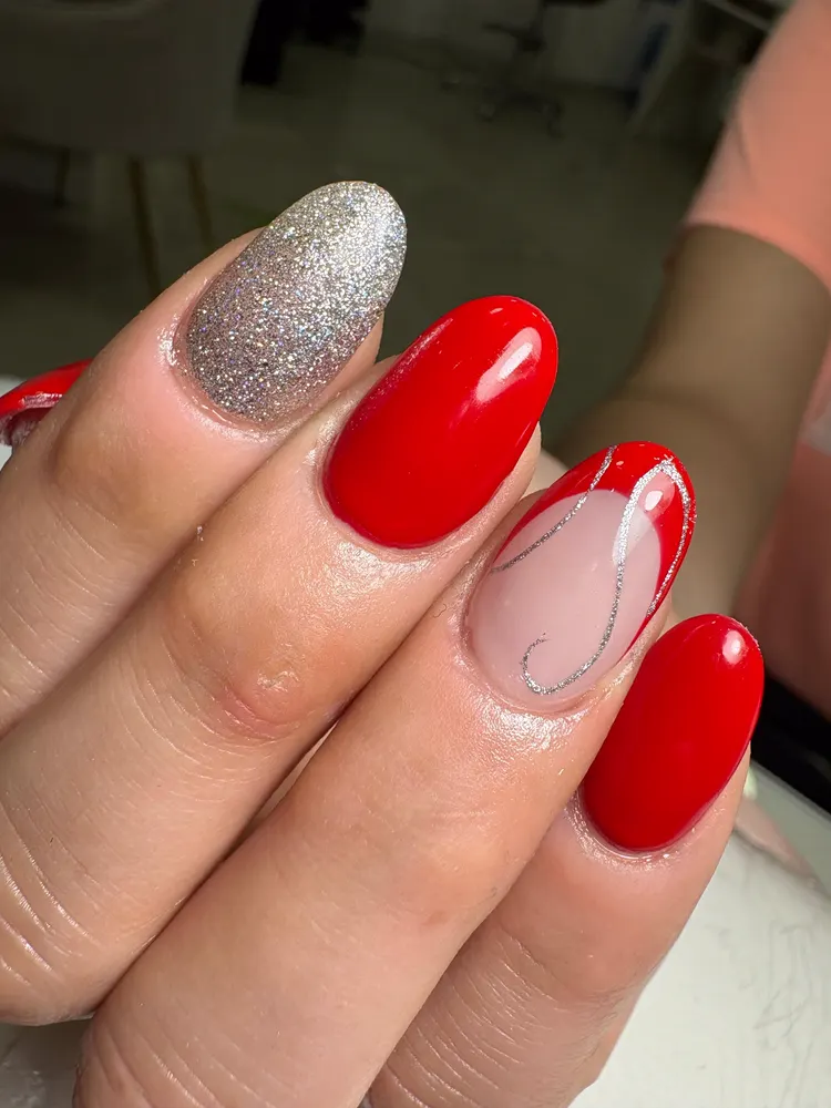 Uñas largas en rojo, con una en plateado brillante y otra con línea fina